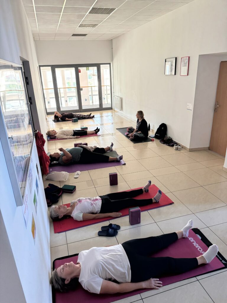Osoby siedzące na korytarzu na matach do pilatesu